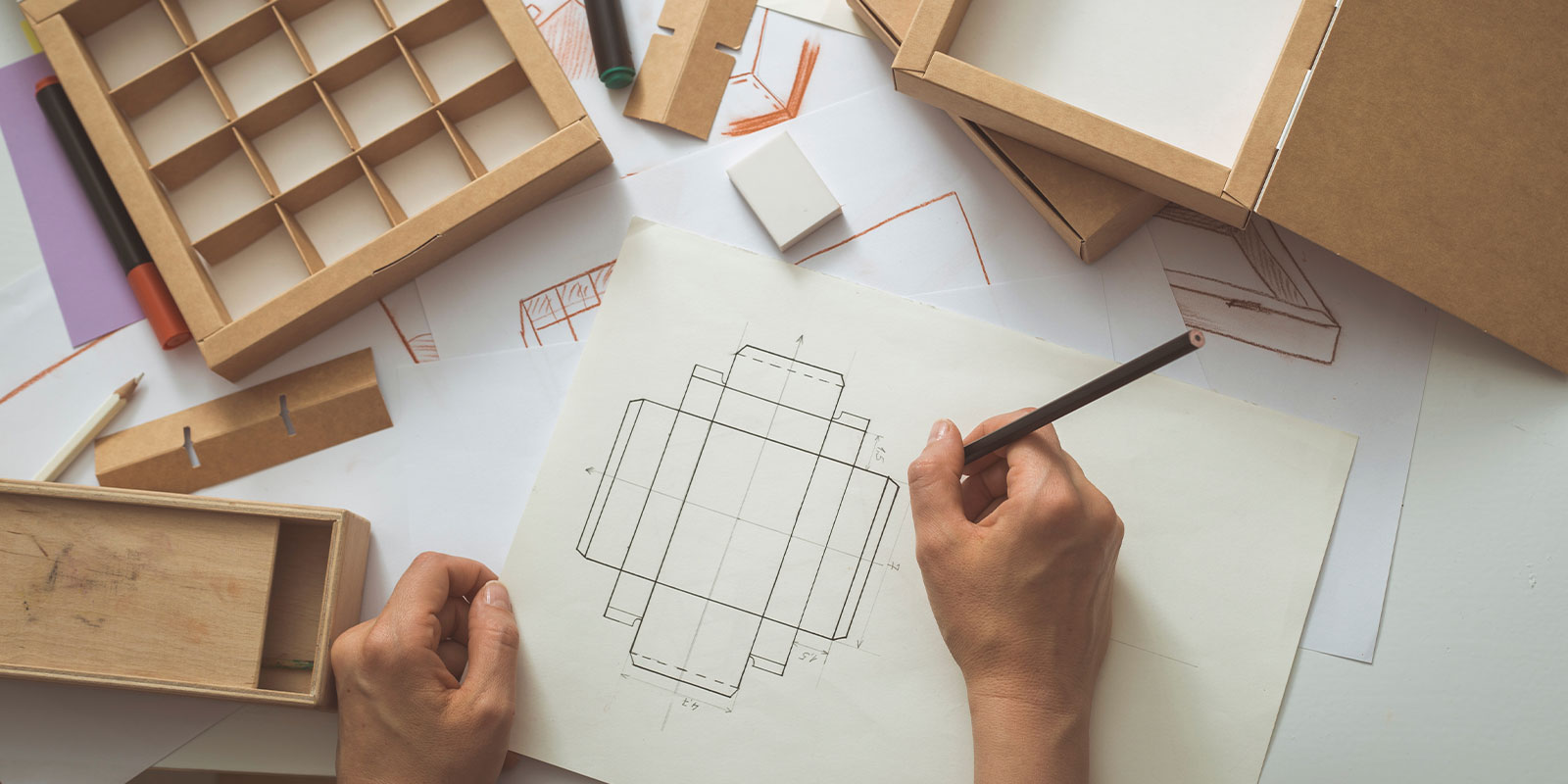 Packaging structure sketch and kraft box samples on a design table